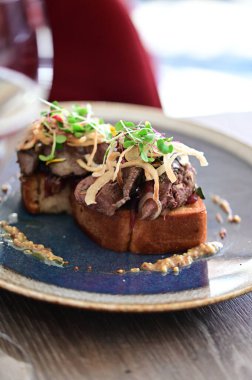 Tavuklu ciğer, karamelli soğan ve mikroyeşillik ile kaplanmış yakın plan kızarmış ekmek, Avrupa mutfağı tarzında servis edilir..