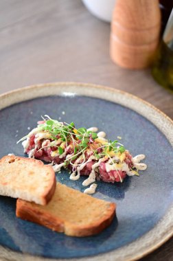 Biftekli tart restoran yemeği olarak servis edilir, öğle veya akşam yemeği için uygundur. Zarif çiğ et lezzeti, modern mutfak tarzıyla sunulan gurme yemek arka planı olarak sunuluyor.