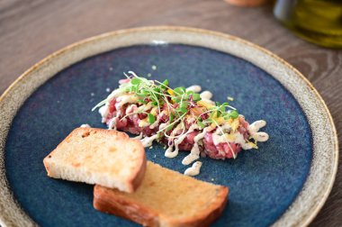 Biftekli tart restoran yemeği olarak servis edilir, öğle veya akşam yemeği için uygundur. Zarif çiğ et lezzeti, modern mutfak tarzıyla sunulan gurme yemek arka planı olarak sunuluyor.