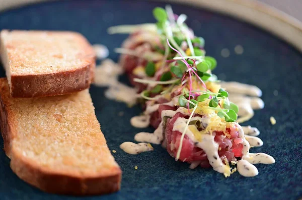 Kızarmış ekmek ve kırsal bir tabakta mikro yeşilliklerle servis edilen, bir restoran ortamında ahşap bir masada sunulan, Avrupa mutfağını ön plana çıkaran,.