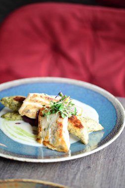 Kızarmış zander, taze malzemeler ve gurme Avrupa mutfağının ön plana çıkarıldığı zarif bir restoranda sunulan garnitür ve soslu bir tabakta servis ediliyor..