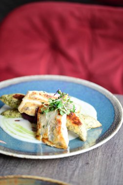 Kızarmış zander, taze malzemeler ve gurme Avrupa mutfağının ön plana çıkarıldığı zarif bir restoranda sunulan garnitür ve soslu bir tabakta servis ediliyor..