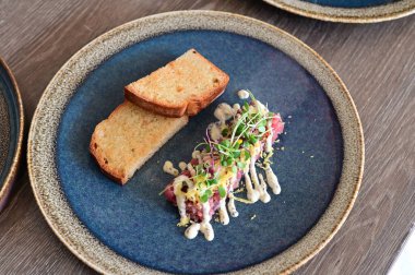 Yakın plan doğranmış dana tartı kremalı mayonez, taze otlar ve narin garnitürle servis edilir. Restoran tarzında zarif bir şekilde kaplanmış, etin detaylı dokusunu vurguluyor..