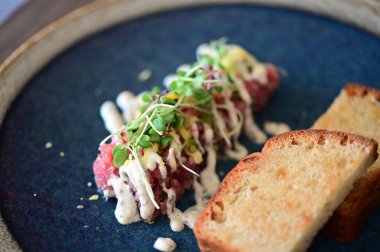 Yakın plan doğranmış dana tartı kremalı mayonez, taze otlar ve narin garnitürle servis edilir. Restoran tarzında zarif bir şekilde kaplanmış, etin detaylı dokusunu vurguluyor..