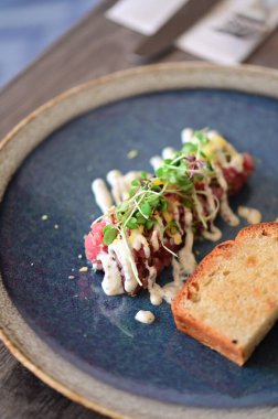 Biftekli tart restoran yemeği olarak servis edilir, öğle veya akşam yemeği için uygundur. Zarif çiğ et lezzeti, modern mutfak tarzıyla sunulan gurme yemek arka planı olarak sunuluyor.