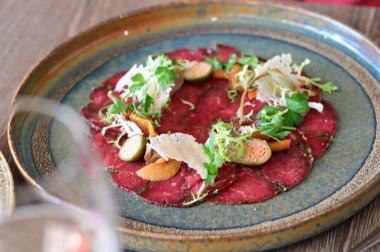 Taze salata ve parmesan peynirli sığır eti carpaccio. Hafif ve zarif bir İtalyan aperatifi ince dilimlenmiş çiğ et, zeytin yağı ve sebzeler gurme yemeği ve Akdeniz mutfağı için mükemmel..