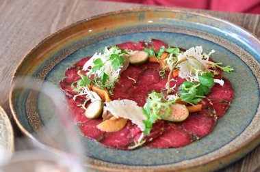 Taze salata ve parmesan peynirli sığır eti carpaccio. Hafif ve zarif bir İtalyan aperatifi ince dilimlenmiş çiğ et, zeytin yağı ve sebzeler gurme yemeği ve Akdeniz mutfağı için mükemmel..