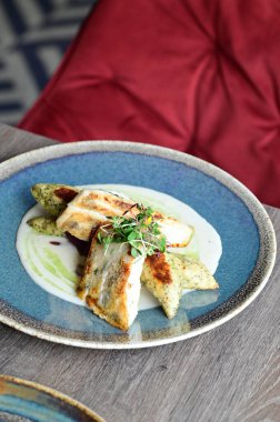 Köy tabaklarında patates gnocchi ile servis edilen kızarmış turna balığı, bir restoran ortamında ahşap bir masada sunuluyor. Arka planda, nefis, sağlıklı bir Avrupa mutfağı ve davetkar ve doğal bir sunum yer alıyor..