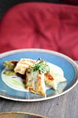 Köy tabaklarında patates gnocchi ile servis edilen kızarmış turna balığı, bir restoran ortamında ahşap bir masada sunuluyor. Arka planda, nefis, sağlıklı bir Avrupa mutfağı ve davetkar ve doğal bir sunum yer alıyor..