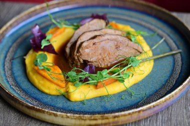 Kabak saflığında kuzu rostosu ve sebzelerle servis edilir. Renkli bir arka planı olan, Avrupa mutfağının altını çizen bir restoran tabağında sunulur..