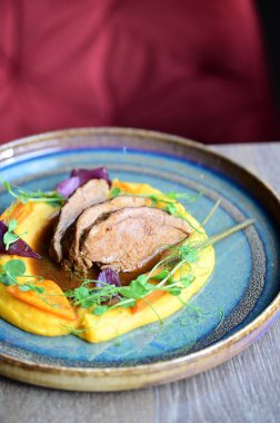 Kabak saflığında kuzu rostosu ve sebzelerle servis edilir. Renkli bir arka planı olan, Avrupa mutfağının altını çizen bir restoran tabağında sunulur..
