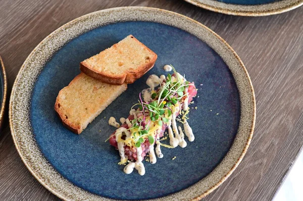 Yakın plan doğranmış dana tartı kremalı mayonez, taze otlar ve narin garnitürle servis edilir. Restoran tarzında zarif bir şekilde kaplanmış, etin detaylı dokusunu vurguluyor..