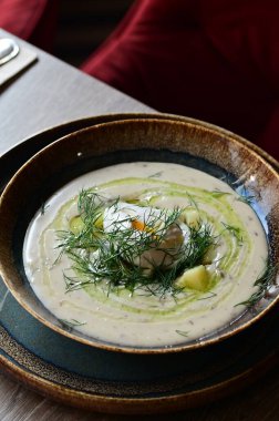 Bir restoranda servis edilen, dereotlu ve yumurtalı kremalı bir çorbanın yukarıdan aşağı görüntüsü. Geleneksel bir Avrupa yemeği, güzelce sunulmuş ve stil verilmiş, otantik tatlar sergileniyor ve ev yapımı yemekler rahatlatıcıydı..
