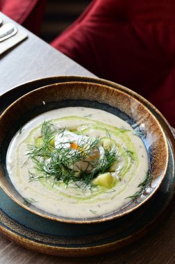 Bir restoranda servis edilen, dereotlu ve yumurtalı kremalı bir çorbanın yukarıdan aşağı görüntüsü. Geleneksel bir Avrupa yemeği, güzelce sunulmuş ve stil verilmiş, otantik tatlar sergileniyor ve ev yapımı yemekler rahatlatıcıydı..