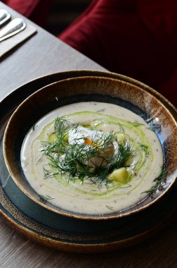 Bir restoranda servis edilen, dereotlu ve yumurtalı kremalı bir çorbanın yukarıdan aşağı görüntüsü. Geleneksel bir Avrupa yemeği, güzelce sunulmuş ve stil verilmiş, otantik tatlar sergileniyor ve ev yapımı yemekler rahatlatıcıydı..