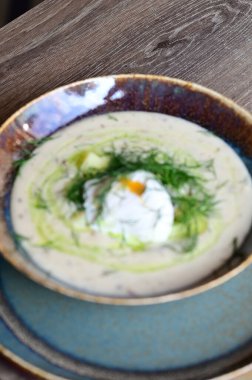 Bir restoranda servis edilen, dereotlu ve yumurtalı kremalı bir çorbanın yukarıdan aşağı görüntüsü. Geleneksel bir Avrupa yemeği, güzelce sunulmuş ve stil verilmiş, otantik tatlar sergileniyor ve ev yapımı yemekler rahatlatıcıydı..