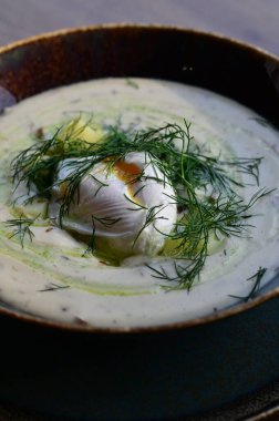 Bir restoranda servis edilen, dereotlu ve yumurtalı kremalı bir çorbanın yukarıdan aşağı görüntüsü. Geleneksel bir Avrupa yemeği, güzelce sunulmuş ve stil verilmiş, otantik tatlar sergileniyor ve ev yapımı yemekler rahatlatıcıydı..