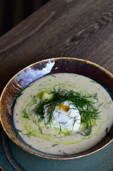Bir restoranda servis edilen, dereotlu ve yumurtalı kremalı bir çorbanın yukarıdan aşağı görüntüsü. Geleneksel bir Avrupa yemeği, güzelce sunulmuş ve stil verilmiş, otantik tatlar sergileniyor ve ev yapımı yemekler rahatlatıcıydı..
