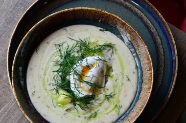 Mantar, yumurta ve patatesle süslenmiş geleneksel Çek çorbası Kulajda 'nın yakından görüntüsü. Bir restoranda ahşap bir masanın üzerinde otantik Çek mutfağı sergiliyor.