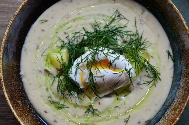 Mantar, yumurta ve patatesle süslenmiş geleneksel Çek çorbası Kulajda 'nın yakından görüntüsü. Bir restoranda ahşap bir masanın üzerinde otantik Çek mutfağı sergiliyor.