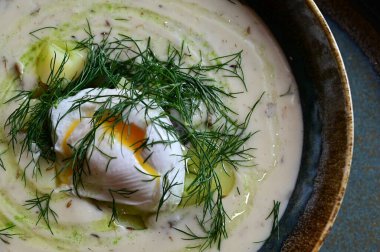 Otlu yumurta çorbası ve arka planda beyaz kasede baharatlar.