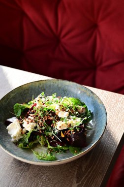 Kızarmış pancar kökü ve kremalı peynirli, yeşillik ve otlarla süslenmiş taze salatanın yakın görüntüsü. Renk ve lezzet dolu canlı ve sağlıklı bir yemek, modern mutfak, sağlıklı beslenme ve yemek fotoğrafçılığı için mükemmel..