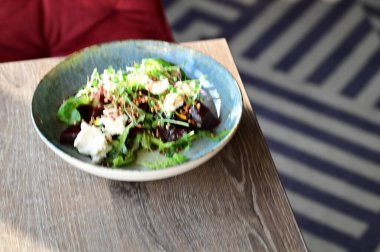 Kızarmış pancar kökü ve kremalı peynirli, yeşillik ve otlarla süslenmiş taze salatanın yakın görüntüsü. Renk ve lezzet dolu canlı ve sağlıklı bir yemek, modern mutfak, sağlıklı beslenme ve yemek fotoğrafçılığı için mükemmel..