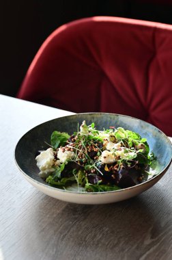 Tahta bir masada sebzeli ve otlu taze salata..