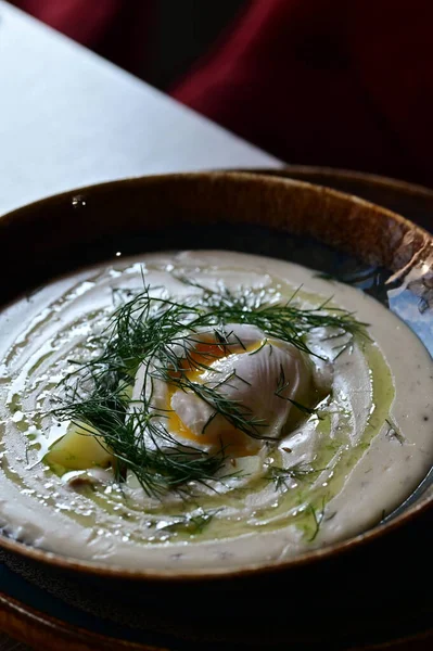 Ekşi kremalı çorba, yeşil soğan ve beyaz tabakta otlar..