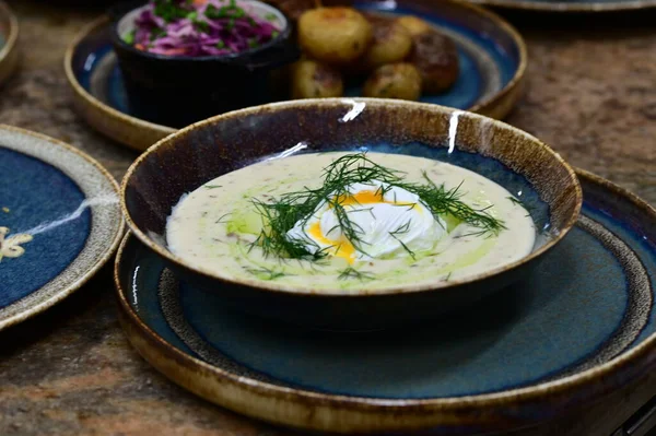 Bir kase taze soğuk çorba, kremalı ve koyu renkli bitkilerle.