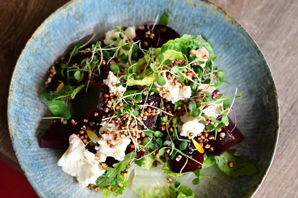 Kızarmış pancar kökü ve kremalı peynirli, yeşillik ve otlarla süslenmiş taze salatanın yakın görüntüsü. Renk ve lezzet dolu canlı ve sağlıklı bir yemek, modern mutfak, sağlıklı beslenme ve yemek fotoğrafçılığı için mükemmel..
