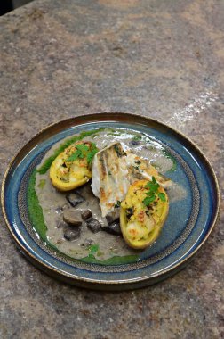 Sotelenmiş mantarlarla servis edilen, taze malzemeler ve canlı dokularla sunulan bir gurme sunumu sunan, aşçılık ve yemek fotoğrafçılığı için mükemmel bir kaplama balık yemeği..