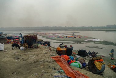 Agra, Hindistan - 8 Ocak 2012: yıkama ve kurutma bez Yamuna Nehri, Agra, Hindistan kumlu kıyısında insanlar.