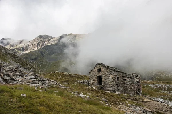 Rovina di vecchio rifugio tra le nuvole. Massiccio del Monte Rosa vicino Punta Indren. Zona di Alagna Valsesia, Italia — Foto Stock
