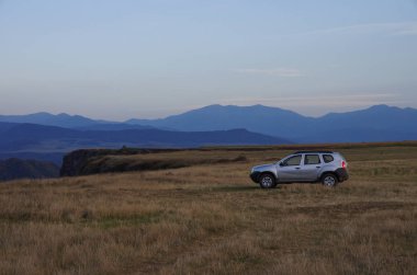Debed Nehri Kanyonu kenarında çayır üzerinde tüm tekerlek sürücü araba, Ermenistan. Günbatımı zamanı.