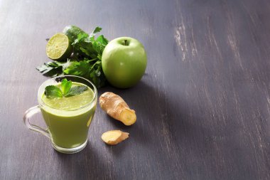 Maydanoz, zencefil, elma, limon ve nane düşük arka ışık ile siyah ahşap bir masa üzerinde bir bardak taze yeşil smoothies. Sağlıklı gıda. Kopya alanı