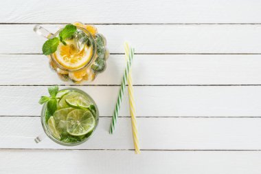 İki cam bardak kireç gelen ev yapımı limonata ve beyaz ahşap rustik zemin üzerine limon, kokteyl boruları ile. Üstten görünüm. Kopya alanı