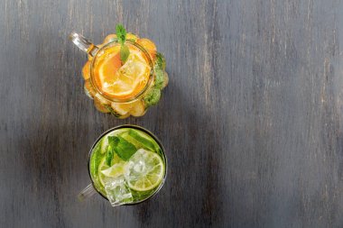 İki cam bardak kireç ve limon siyah bir rustik ahşap zemin üzerine ev yapımı limonata ile. Üstten görünüm