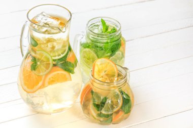 Cam sürahi ve bardak taze limonata ile parlak ışık Beyaz ahşap rustik tahtalar üzerinde durmak. Kopya alanı