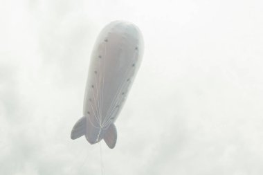 Beyaz şişme zeplin ile bulutlu gri bir gökyüzü arka plan üzerinde bir logo için bir yer. Kopya alanı