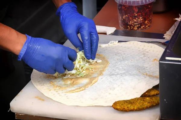 Cook bir burger hazırlar ve eldiven salata ekmek kek üzerine ellerini koyar. Sokak ticaret