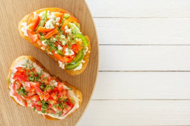 Bruschetta taze domates, tatlı biber ve beyaz tahtalar üzerinde keçi peyniri. Üstten görünüm.