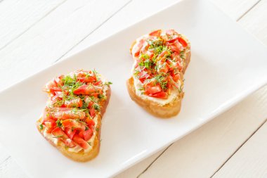 Taze domates ve peynirle beyaz tabakta Bruschetta.
