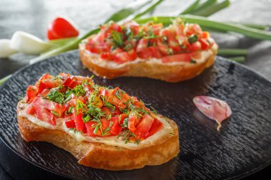 Bruschetta taze domates ve peynirle siyah bir plaka üzerinde. Yakın çekim