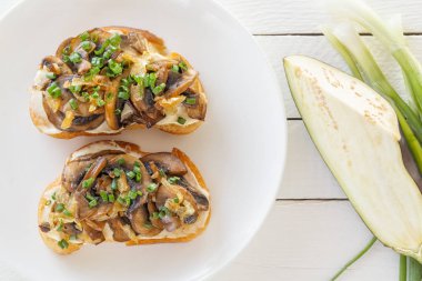 İki taze bruschettes mantar yalan soyulmuş patlıcan yanındaki bir tabakta ve soğan Beyaz ahşap zemin üzerinde. Üstten görünüm