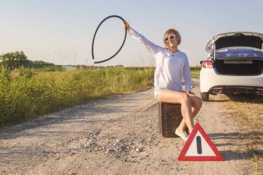 güzel kız sürücü yanındaki kırık bir araba benzin için boş bir teneke kutu içinde güneşin ışınları kırsal bir yolda yardım için beklerken oturur. Tonda. Portre. Kopya alanı