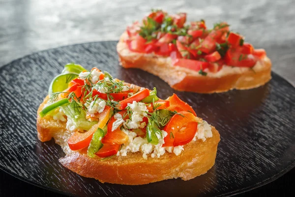 Bruschetta kırmızı tatlı biber ve keçi peyniri siyah bir arka plan ile. Yakın çekim