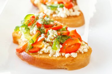 Bruschetta kırmızı tatlı biber ve keçi peyniri beyaz bir plaka ile. Yakın çekim