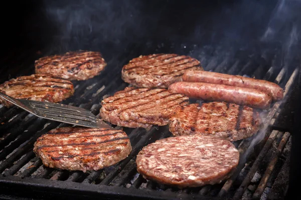 Cooking burgers on hot coals with smoke. Close-up