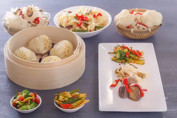 Dishes of Chinese cuisine in assortment. Steam dumplings, noodles, salads, vegetables, mushrooms, seafood